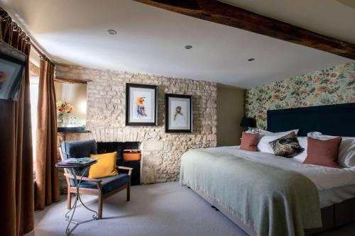 1 dormitorio con 1 cama grande y 1 silla en The Wheatsheaf Inn, en Bourton on the Water