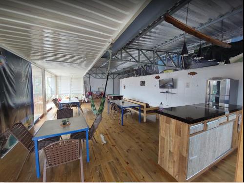 a large room with tables and chairs and a kitchen at Trip Adventure Hostel in Porto Belo