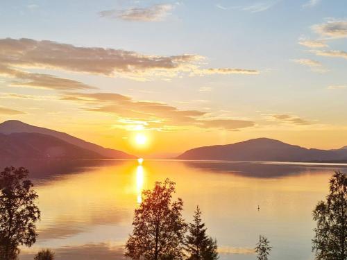 a sunset on a lake with mountains in the background at 6 person holiday home in Sandhornøy-By Traum in Røssnes