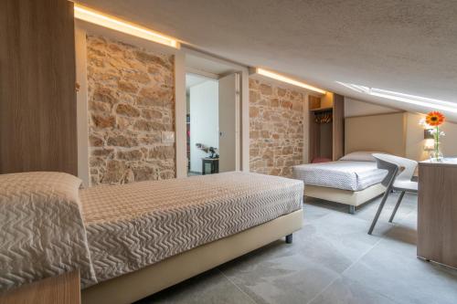 Goloritzè Room and Breakfast في بوناي: غرفة نوم بسريرين وجدار حجري