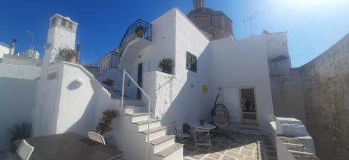 a white building with stairs and a table at Dimora Lavinia Casa vacanze Centro storico Ostuni in Ostuni