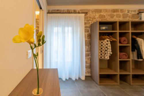 a vase with a yellow flower on a table in a room at Goloritzè Room and Breakfast in Baunei
