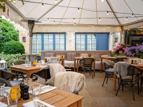 een restaurant met houten tafels, stoelen en verlichting bij The Wheatsheaf Inn in Bourton on the Water