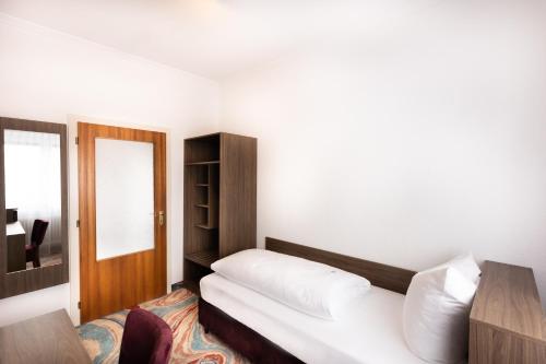 a bedroom with a white bed and a mirror at Firzlaff's Hotel in Neumünster