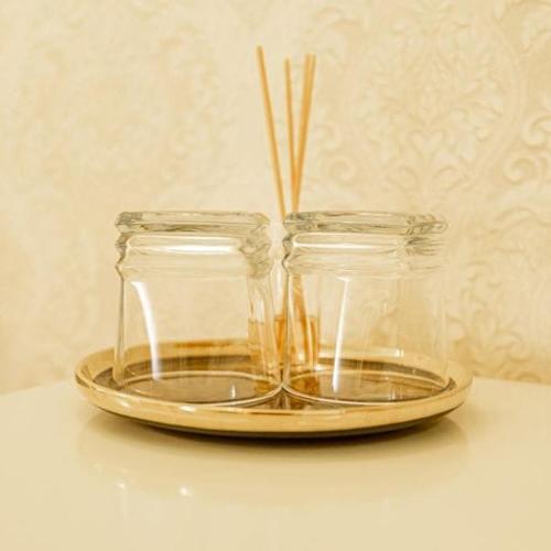 two glass jars on a gold plate with sticks in them at Grand Hotel Baroc in Zalău