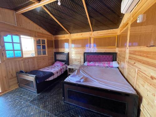 two beds in a room with wooden walls at Sina Star Camp in Nuweiba