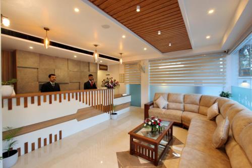 two men in a lobby with a couch and a table at Hotel NovArk Munnar in Kallar Vattiyar