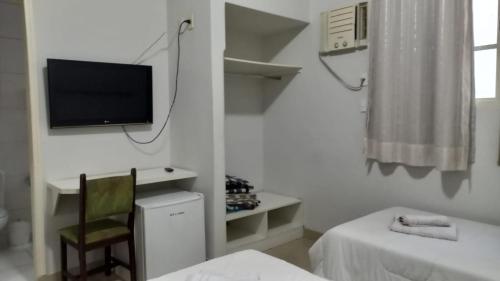 a white room with a tv and a chair at Alzira Plaza Hotel in São Lourenço