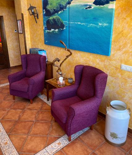 two purple chairs and a table in a room at Hotel Rural El Texeu in Llanes