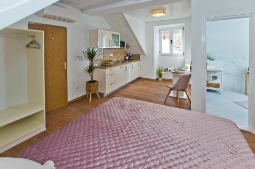 a bedroom with a pink bed and a kitchen at *Beautiful, centrally located studio apartment* in Hvar