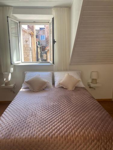 Schlafzimmer mit einem großen Bett und einem Fenster in der Unterkunft *Beautiful, centrally located studio apartment* in Hvar