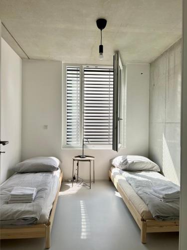 two beds in a bedroom with a table and a window at Weinberg-Design-Apartment Stuttgart-Fellbach in Fellbach
