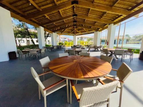 einen Holztisch und Stühle auf einer Terrasse mit Tischen in der Unterkunft Estudio Top Praia do Forte in Mata de Sao Joao