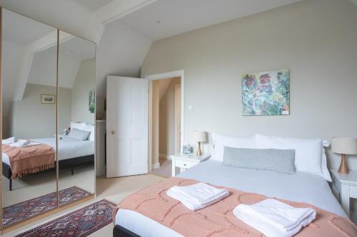 a bedroom with a large bed and a mirror at Spacious 3BR Victorian Cheltenham loft flat in Cotswolds Sleeps 8 - FREE Parking in Cheltenham