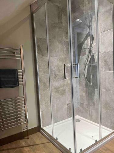 a shower with a glass door in a bathroom at Mid Antrim Modern Apartment in New Ferry