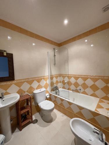 a bathroom with a toilet and a tub and a sink at Hotel Rural El Texeu in Llanes