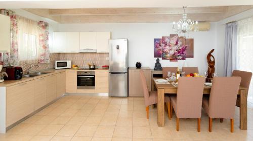 a kitchen with a table and a refrigerator at Posidonia Luxury Villas Kolympia in Kolimbia