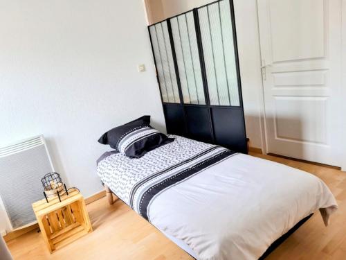 a bedroom with a bed with white sheets and black pillows at maison de vacances 5 personnes in LʼOie