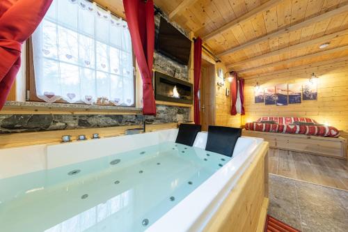 ピエーヴェ・ディ・カドーレにあるAL RANCH WELLNESS CADORE DOLOMITI APARTMENTS vicino Cortina e Misurina Tre Cime Lavaredoの- ジャグジー付きの客室の真ん中