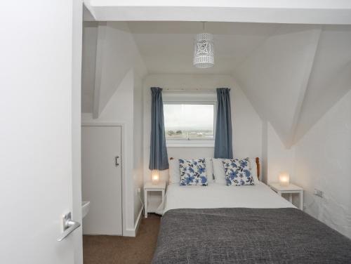 阿伯索赫的住宿－Cilan - 2 Ty'n Don，一间卧室配有一张带蓝色窗帘的床和一扇窗户