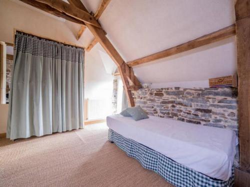 - une chambre avec un lit et un mur en pierre dans l'établissement Chambres d'hôtes - Au Domaine des Camélias, à Pluméliau