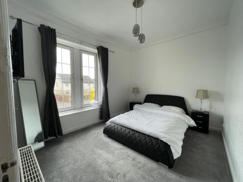 a bedroom with a bed and a large window at Premier Apartment C in Broxburn