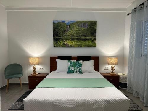 a bedroom with a white bed and two lamps at Paradise Apartments I in Santa Cruz das Flores