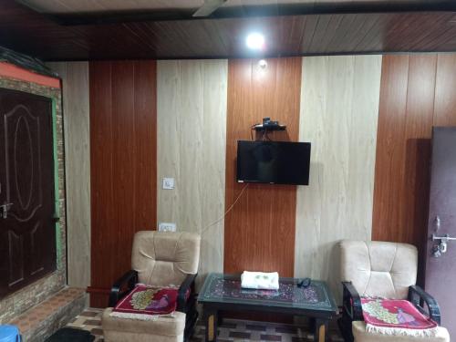 a room with two chairs and a tv on a wall at SAMAUN Homestay in Kurchhola