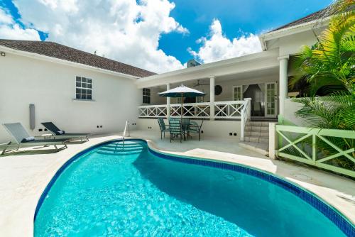 a swimming pool in front of a house at Hullabaloo in Saint James