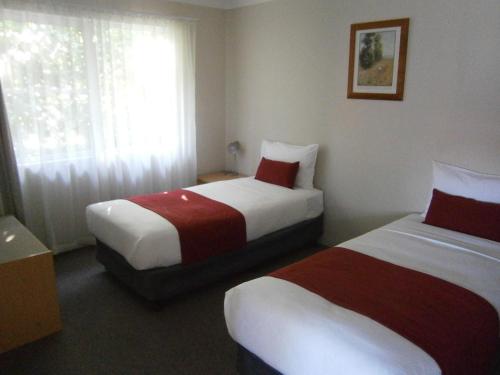 a hotel room with two beds and a window at George Bass Motor Inn in Nowra