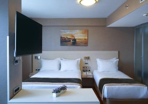 イスタンブールにあるホテル トロヤのベッド2台とテーブルが備わるホテルルームです。