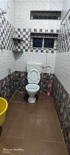 a bathroom with a toilet in a room with tiles at Rainbow Comforts in Chikmagalūr