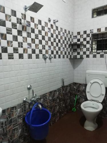 a bathroom with a toilet and a bucket in it at Rainbow Comforts in Chikmagalūr