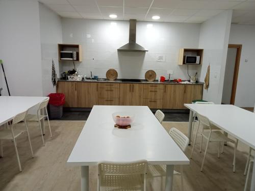 a kitchen with white tables and chairs in a room at Albergue O Trisquel in O Pedrouzo