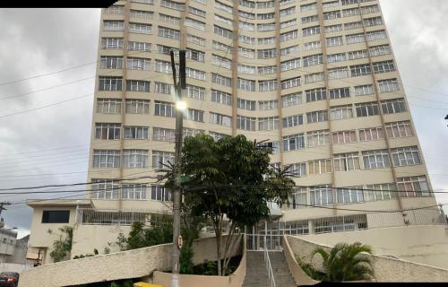 a tall building with a palm tree in front of it at Apezinho da Soltony em Peruibe in Peruíbe