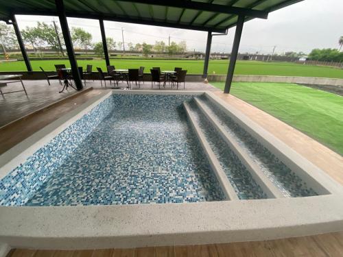 a pool in a pavilion with chairs and tables at 慕研安農民宿 包棟 KTV 游泳池 羅東運動公園 22p in Yilan City