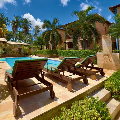 three lounge chairs sitting next to a swimming pool at Hotel Vento Brasil in Paracuru