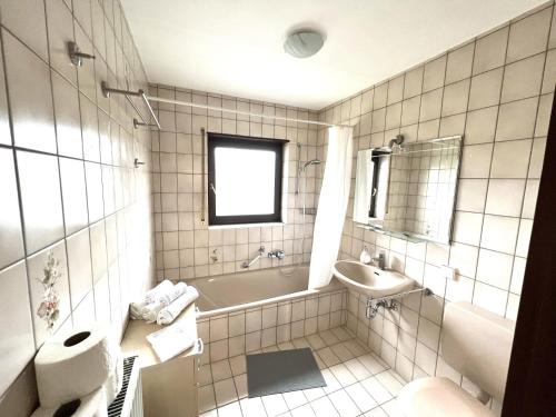 La salle de bains blanche est pourvue d'une baignoire et d'un lavabo. dans l'établissement Große Ferienwohnung, Apartment in Leimen WeHome Komfort, à Leimen