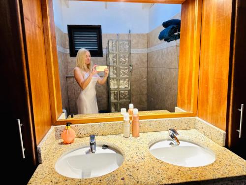 a woman taking a picture of herself in a bathroom mirror at Tip! Blue Bay Beachvilla 12 - Blue Bay Resort in Sint Michiel