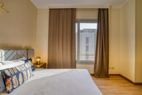 a bedroom with a bed and a large window at The Suites near AUC by Elegant Hospitality in Cairo