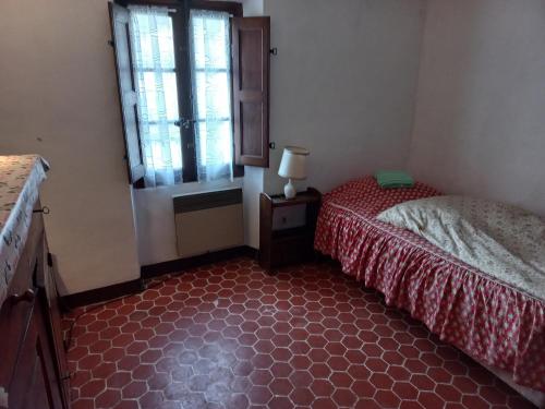 Schlafzimmer mit einem Bett und einem Fenster in der Unterkunft Chambre dans maison de caractère in La Bastide