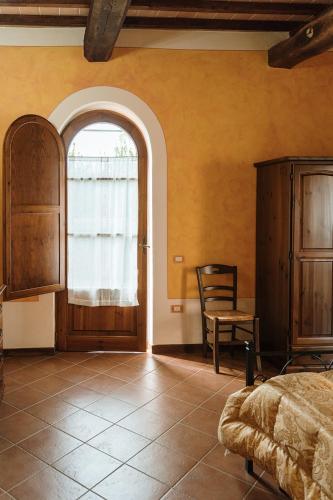 a bedroom with a bed and a chair and a window at Villa Nottola in Montepulciano