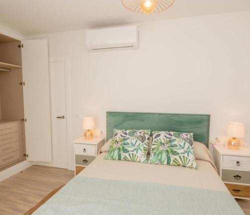 een witte slaapkamer met een bed met een groen hoofdeinde bij Apartamento Jacaranda in La Herradura