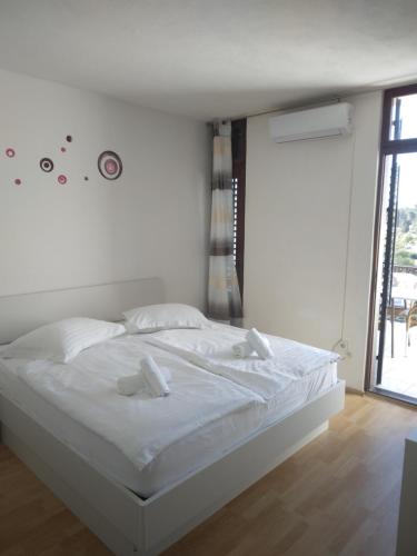 1 dormitorio con 1 cama con sábanas blancas y ventana en Ivanka Apartments, en Vrboska