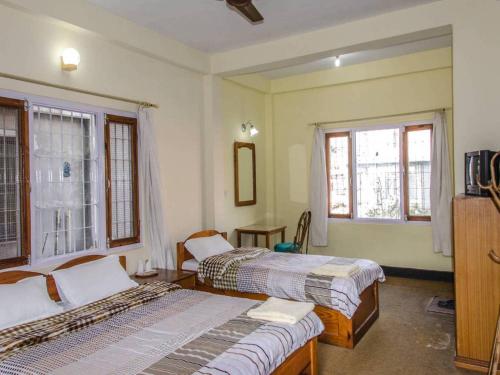 a bedroom with two beds and two windows at Placid Valley Lodge in Pokhara