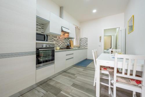 eine Küche mit weißen Schränken sowie einem Tisch und Stühlen in der Unterkunft La casina della Pia in Viareggio