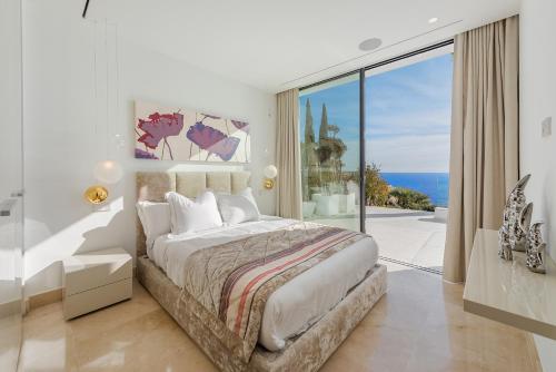 a bedroom with a large bed with a view of the ocean at Blue Sky Mallorca Luxury Villa in Andratx