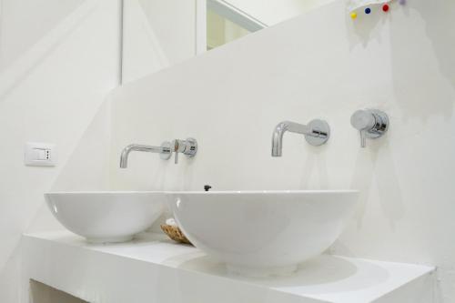 two sinks in a white bathroom with two faucets at La Maison Boheme by Fra Cielo e Mare in Cagliari
