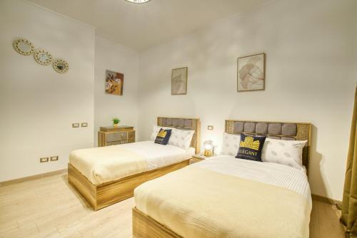 two beds in a room with white walls at The Suites near AUC by Elegant Hospitality in Cairo