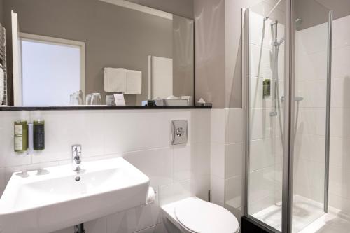 a white bathroom with a sink and a shower at Batschari Palais Baden-Baden in Baden-Baden
